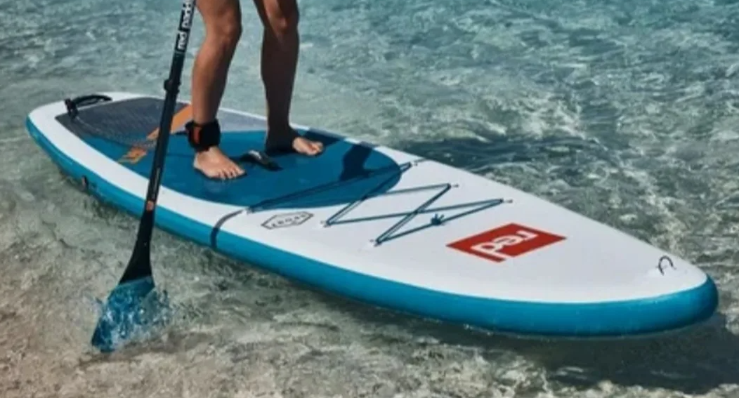 Paddler exploring a rocky Balearic cove on a SUP board